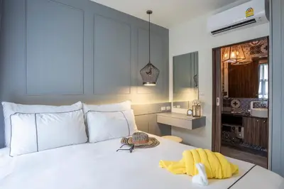 a bedroom with a white bed with a yellow towel on it at Surin Beach Residence - Official Account in Surin Beach