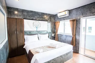 a bedroom with a large bed with a tree on the wall at Happy 99 Guest house in Patong Beach