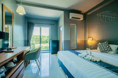 a hotel room with a large bed and a desk at The Rubber Hotel Phuket in Thalang