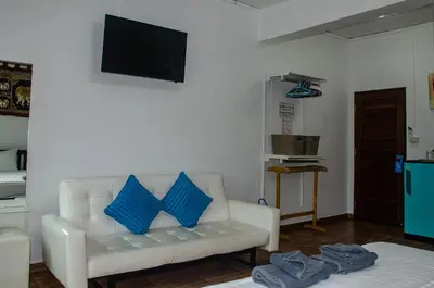 a living room with a white couch with blue pillows at Allstar Guesthouse in Karon Beach