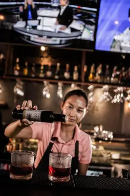 a woman is pouring a drink into two glasses at Big Boys' Bed & Burger - Patong Beach in Patong Beach