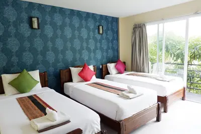 a hotel room with three beds and a window at Phi Phi Maiyada Resort in Phi Phi Don
