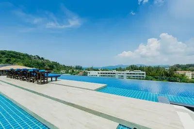 a swimming pool with tables and chairs on a building at The Aristo by Holy Cow, studio, mountain view in Surin Beach