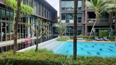 a swimming pool in front of a building with palm trees at Lucky Holidays in Saturdays Residence in Rawai Beach