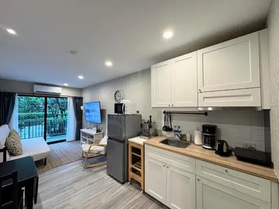 a kitchen with white cabinets and a living room at The Title Residencies Naiyang by Beringela in Nai Yang Beach