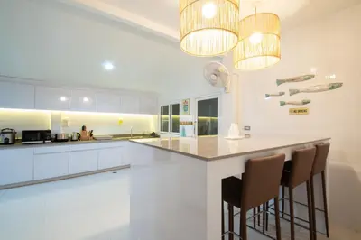 a kitchen with white cabinets and a bar with stools at Rudi House in Patong Beach