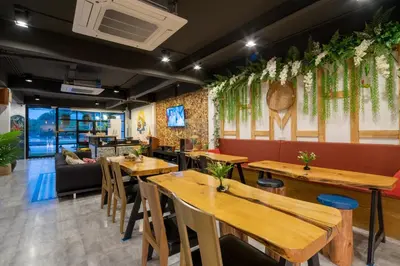 a restaurant with wooden tables and a couch at Hanuman VIP Hostel in Bang Tao Beach