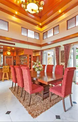 a dining room with a wooden table and red chairs at Thai style villa with very beautiful private pool in Kamala Beach
