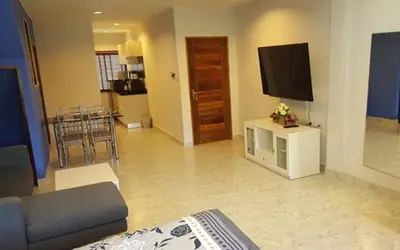 a living room with a couch and a television on a table at Oasis Apartments & Bar in Karon Beach