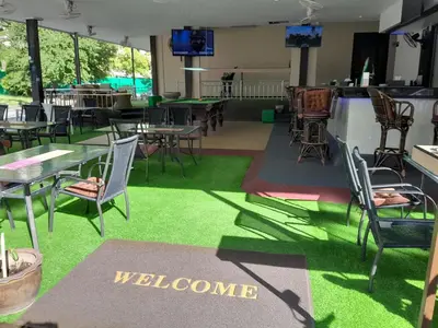 a restaurant with tables and chairs and a welcome sign at Oasis Guesthouse & Bar in Karon Beach