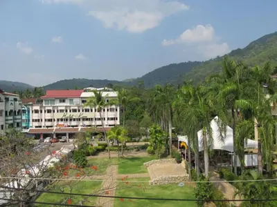 a view of a resort with palm trees and a building at Oasis Guesthouse & Bar in Karon Beach