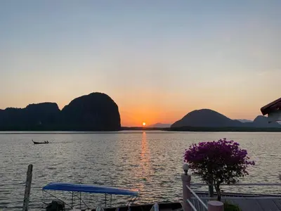 a sunset over a lake with a boat in the water at Jamesbond Bungalow Koh Panyee in Ko Panyi