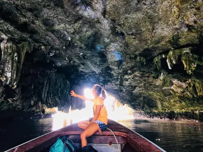 a girl sitting on a boat in a cave at Jamesbond Bungalow Koh Panyee in Ko Panyi