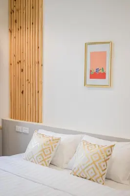 a bed with white pillows and a picture on the wall at Isara Boutique Hotel and Cafe in Phuket Town