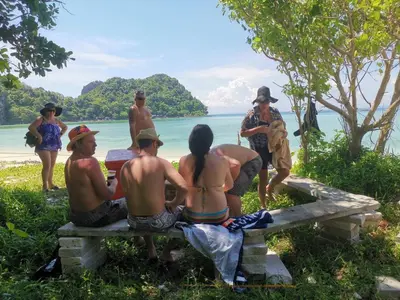 a group of people sitting on a bench at the beach at PP Red Tuna Hut in Phi Phi Don