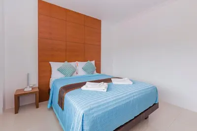 a bedroom with a blue bed with a wooden headboard at Sukcheewa Residence Phuket in Patong Beach