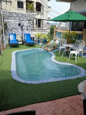 a pool with chairs and a table and an umbrella at Patong Sunbeach Mansion in Patong Beach