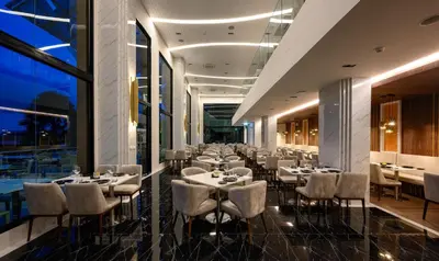 a restaurant with tables and chairs in a room at Mida Grande Resort Phuket Official Account in Surin Beach