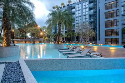 a pool with lounge chairs and palm trees and buildings at Citygate Kamala Resort and Residence - Official Account in Kamala Beach