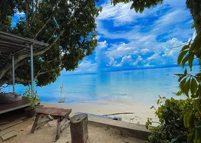 a bench on the beach with a view of the ocean at The Parlour Krabi in Klong Muang Beach