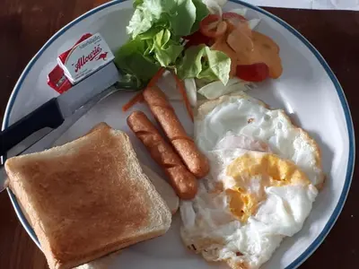 a plate of breakfast food with eggs sausage and toast at We Love Kata in Kata Beach