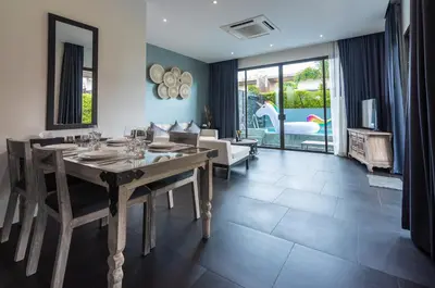 a dining room with a table and a living room at The Infinity Private Pool Villa in Phuket Town