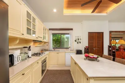 a kitchen with white cabinets and a bowl of fruit on the counter at VILLA LETI 22 meters Pool Naiharn Beach in Rawai Beach