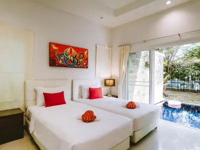 two beds with red pillows in a bedroom with a window at Layantara Villas in Layan Beach