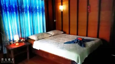 a bedroom with a bed with blue curtains at Najjamee Bungalows in Ko Yao Noi
