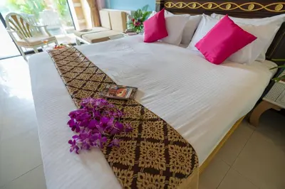 a bed with pink pillows and a bouquet of flowers on it at Ayodhaya Palace Beach Resort - SHA Plus certified in Ao Nang Beach