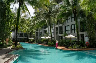 a woman standing next to a swimming pool with palm trees at Amazing Apartment in Diamond Condominium, Bang Tao Beach in Bang Tao Beach