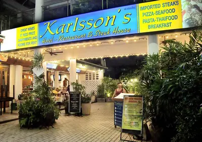 a woman standing in front of a store with plants at Patong Karlssons Hotel in Patong Beach