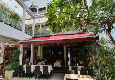 a restaurant with tables and chairs in a building at Patong Karlssons Hotel in Patong Beach