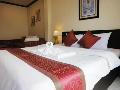 a bedroom with two large white beds with red pillows at Patong Karlssons Hotel in Patong Beach
