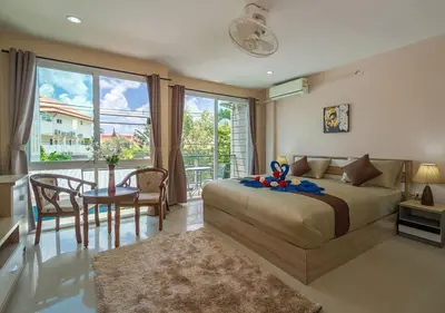 a bedroom with a bed and a table and chairs at Tropical Sands in Nai Harn Beach