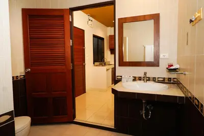 a bathroom with a sink and a toilet and a mirror at Katanoi Resort in Kata Beach