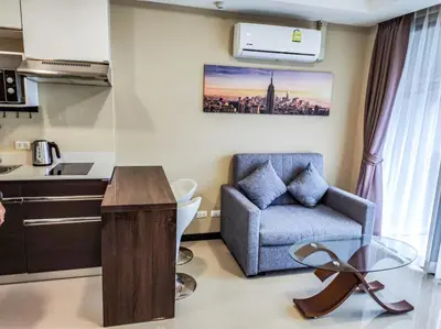 a living room with a chair and a kitchen at MBC Mai Khao Beach Condotel LUXURY APARTMENTs in Phuket Town