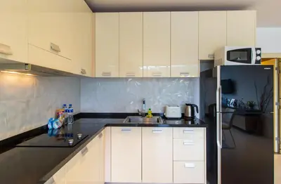 a kitchen with white cabinets and a black refrigerator at Icon Park Apartments - Kamala Beach in Kamala Beach