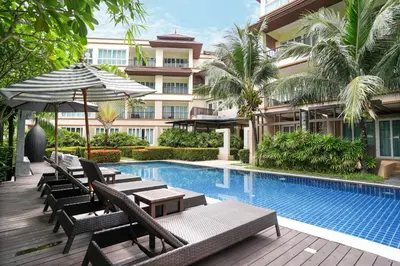 a hotel with a swimming pool with chairs and an umbrella at Hotel COCO Phuket Bangtao Beach in Bang Tao Beach