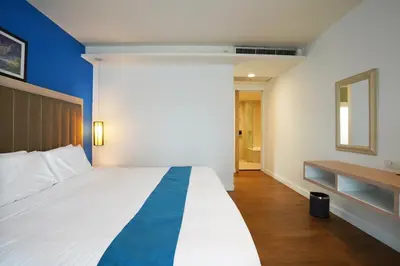 a bedroom with a large white bed with a blue stripe at Hotel COCO Phuket Bangtao Beach in Bang Tao Beach