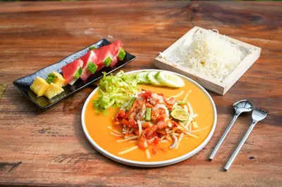 a plate of food sitting on a wooden table with food at Hotel COCO Phuket Bangtao Beach in Bang Tao Beach