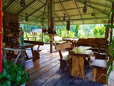 a wooden floor with tables and benches in a pavilion at Koom Kachanaan in Ban Nong Thale