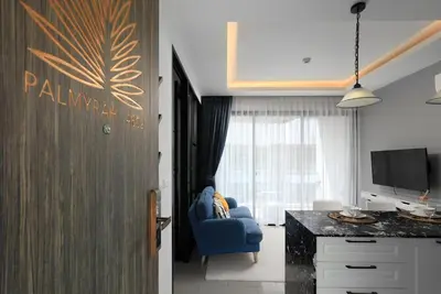 a living room with a blue chair and a television at The Sea View room in Palmyrah Surin by Holy Cow in Surin Beach