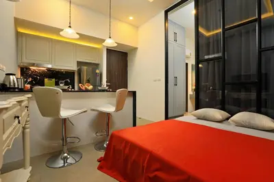 a bedroom with a red bed and a kitchen at The Palmyrah Surin by Holy Cow, 1-BR, courtyard or pool view in Surin Beach