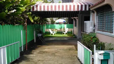 a green fence with chairs and an umbrella in a yard at Bangtao Rooms in Bang Tao Beach