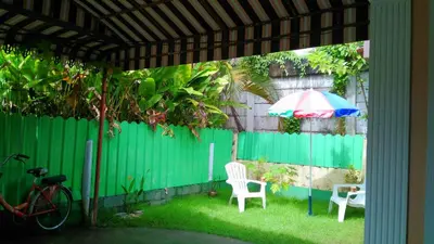 a patio with a green fence and an umbrella and chairs at Bangtao Rooms in Bang Tao Beach