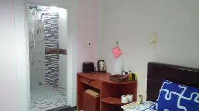 a bedroom with a desk and a glass shower at Bangtao Rooms in Bang Tao Beach