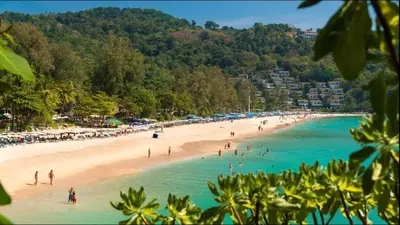 a beach with a bunch of people in the water at Kata gardens luxury 2bedroom 4B Near Kata Noi Beach in Kata Beach
