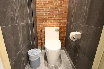a bathroom with a toilet and a trash can at GN Capsule Hostel Patong in Patong Beach