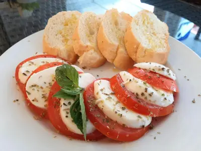 a plate of food with tomatoes and bread on it at GN Capsule Hostel Patong in Patong Beach